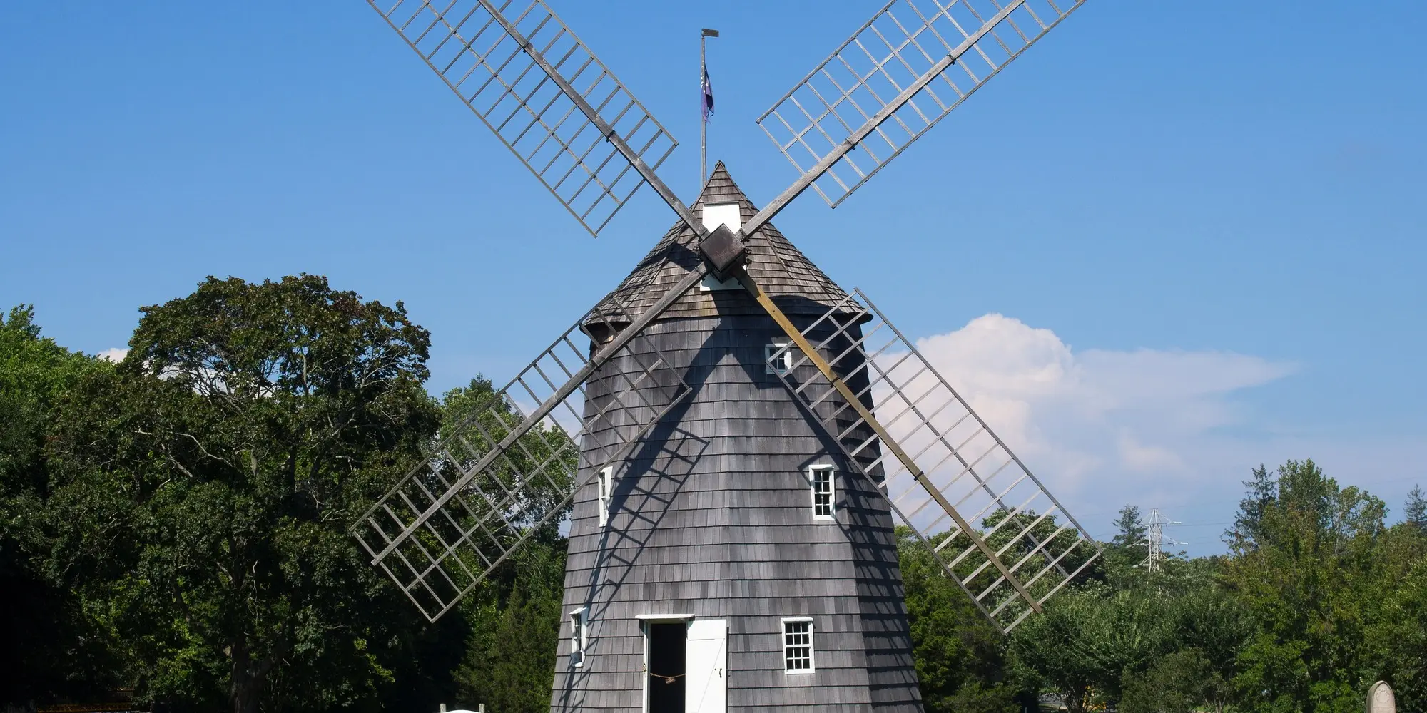 Old Hook Mill, a shingled windmill, against a blue sky in East Hampton