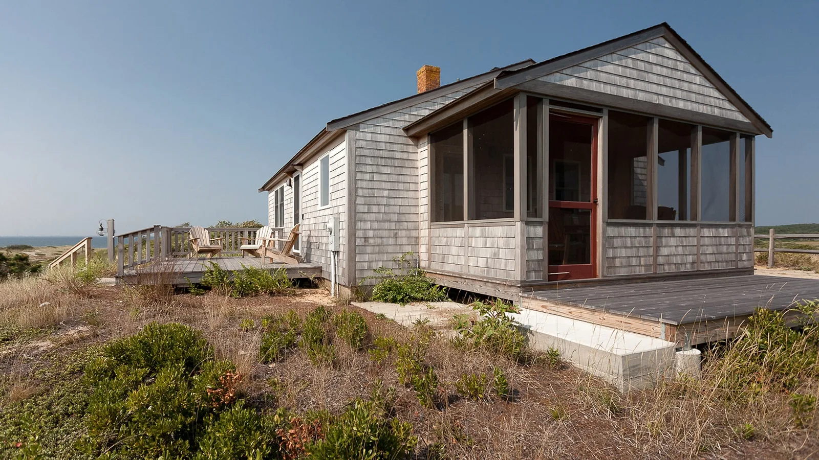 Gray-shingled cottage with screened porch on dunes