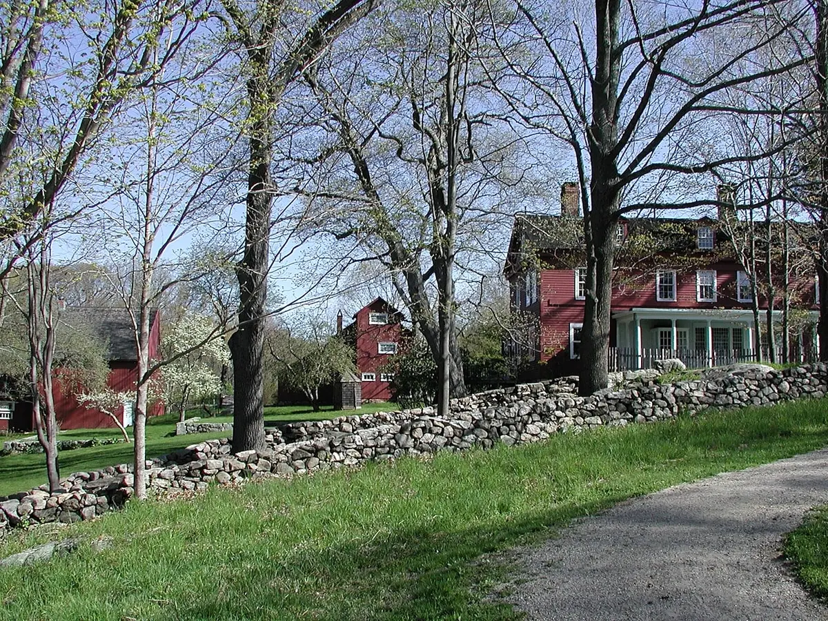 Path past stone wall and trees to houses